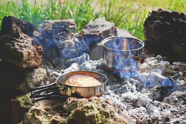 pots cooking on campfire coals