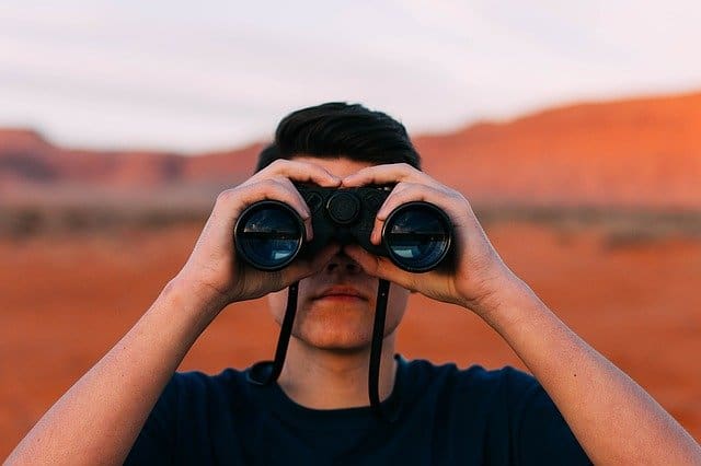 observant man looking thru binoculars