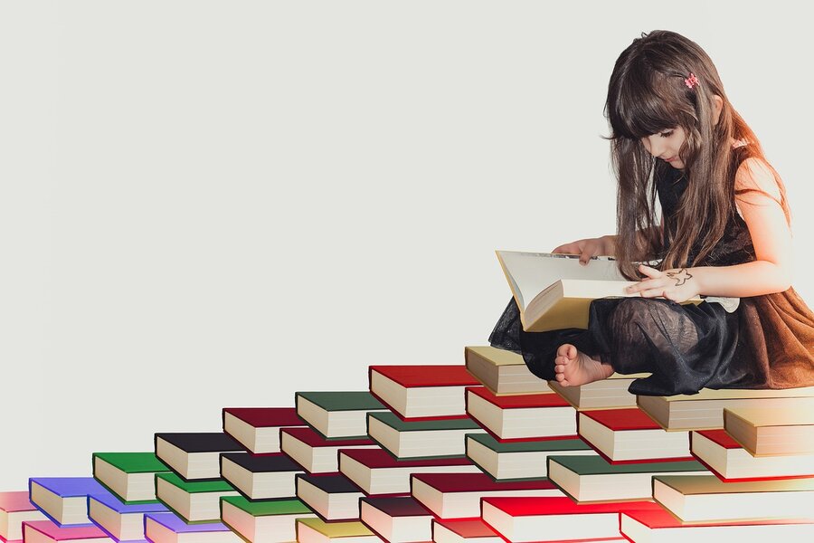 keen mind girl reading book on book pyramid