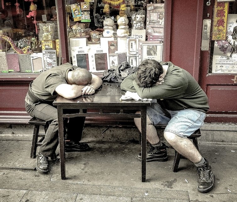 two exhausted men sleeping on table